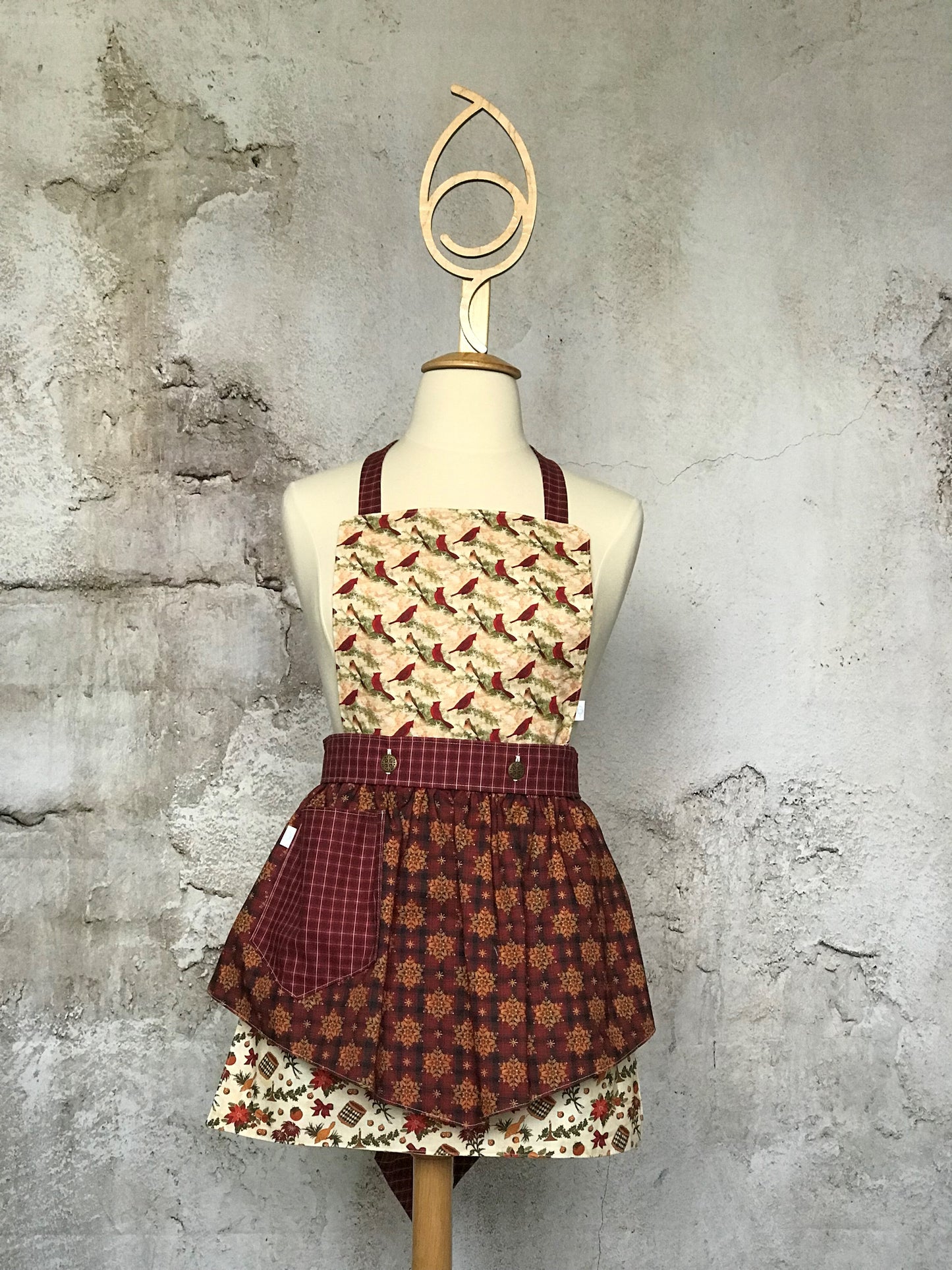 Deby’s Diva Apron™ is a patent pending convertible kitchen apron that can be worn 24 different ways by using the buttons on the waistband to flip, add or subtract the bib and both apron front and back. Featuring generously sized pockets, 100% high quality cotton fabric, and long waist and neck ties to make this apron well suited for most figures. Old-fashioned Christmas prints that include drums, horns, poinsettias, cardinals, holly and snowflakes.