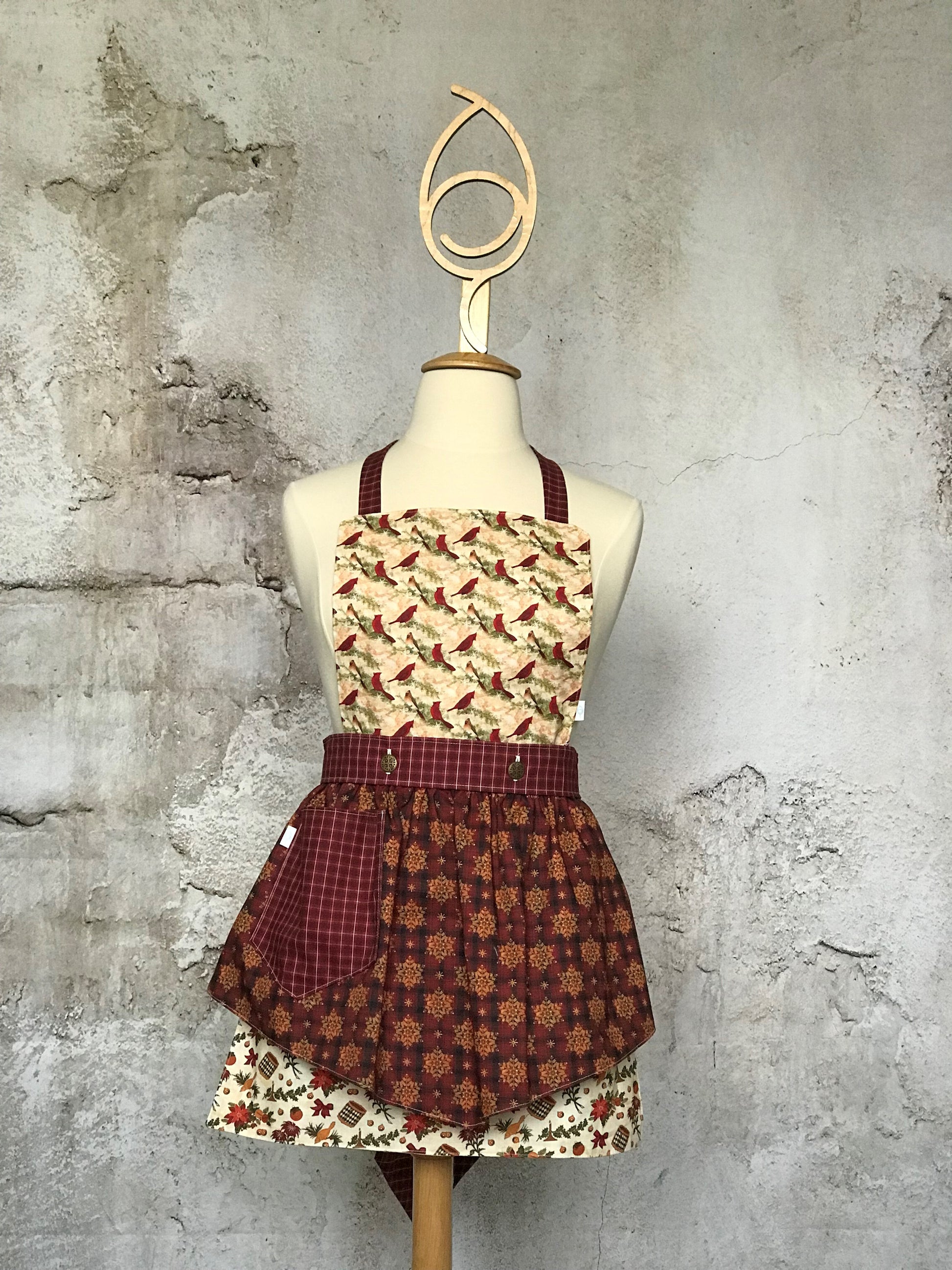 Deby’s Diva Apron™ is a patent pending convertible kitchen apron that can be worn 24 different ways by using the buttons on the waistband to flip, add or subtract the bib and both apron front and back. Featuring generously sized pockets, 100% high quality cotton fabric, and long waist and neck ties to make this apron well suited for most figures. Old-fashioned Christmas prints that include drums, horns, poinsettias, cardinals, holly and snowflakes.