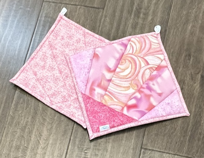 Dots of Flowers Rae's™ Diva Potholder is 9.5 inches square and covered in tiny dotted flowers on cream and lavender background and strawberry flowers on pale blue and black backgrounds with a backing of tiny dotted soft green.