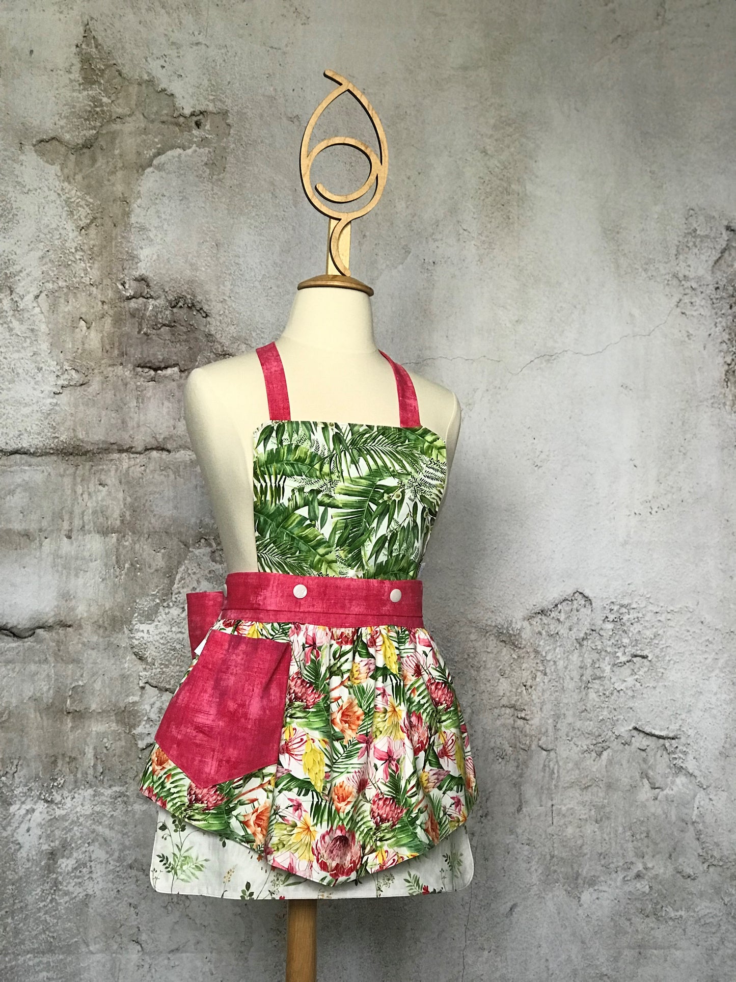 Deby’s Diva Apron™ is a patent pending convertible kitchen apron that can be worn 24 different ways by using the buttons on the waistband to flip, add or subtract the bib and both apron front and back. Featuring generously sized pockets, 100% high quality cotton fabric, and long waist and neck ties to make this apron well suited for most figures. Brightly colored flowers, palm leaves and stripes make this apron a happy burst of sunshine.